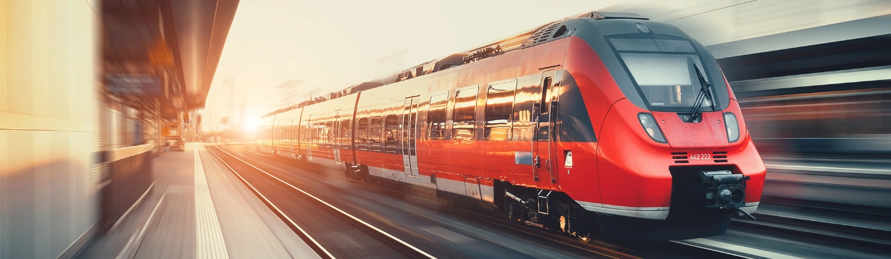 Roter Zug fährt durch einen Bahnhof