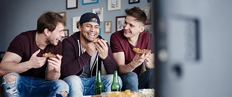 3 Freunde essen Snacks und verfolgen Fußball-EM 2024