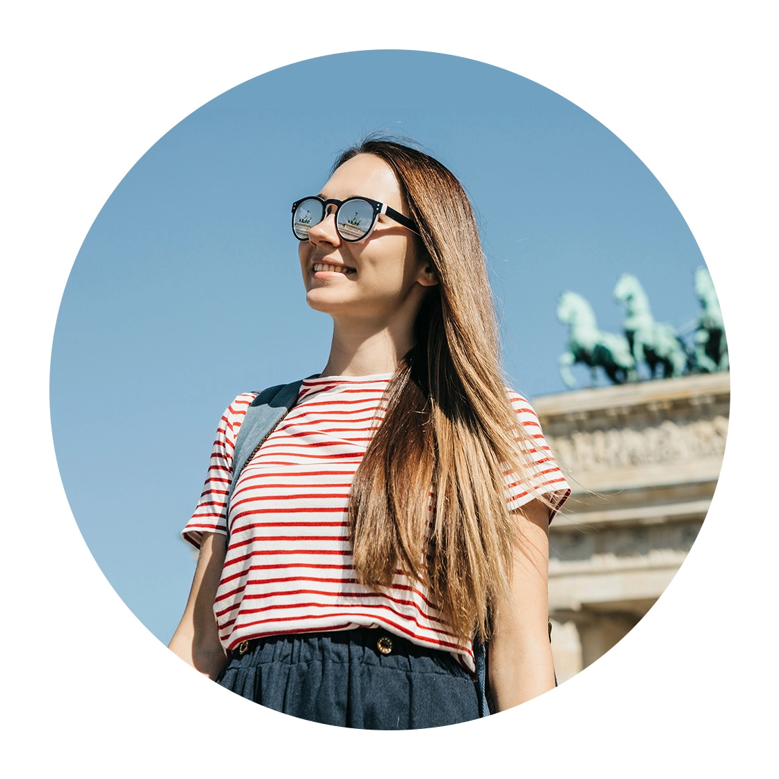 Eine Frau steht lächelnd vor dem Brandenburger Tor in Berlin