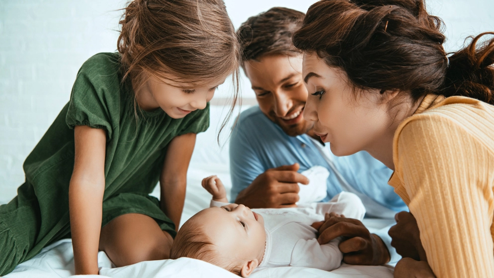 Eine Familie beugt sich über das Neugeborene