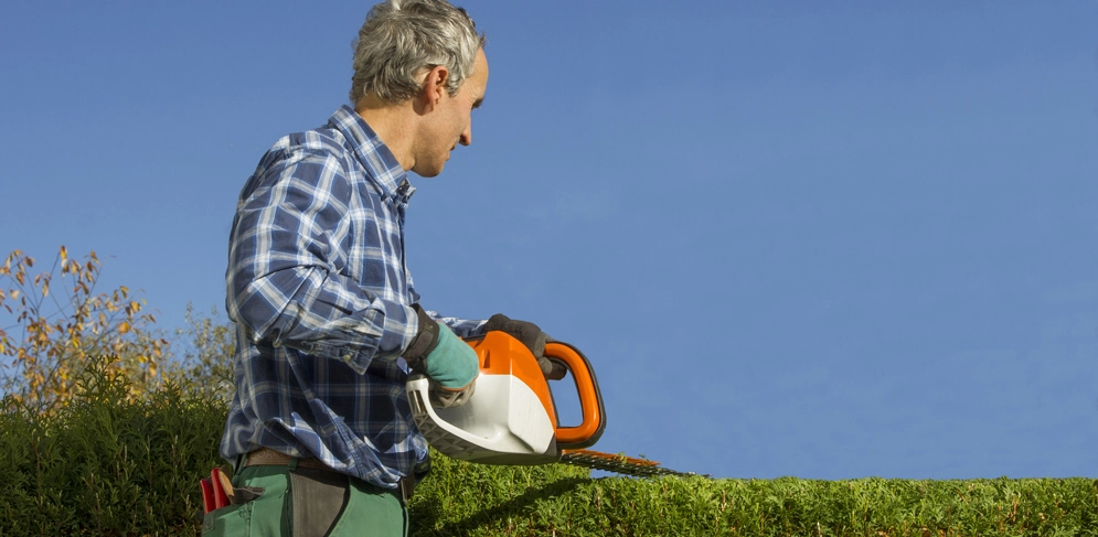 Ein Mann benutzt die neue Heckenschere im Garten