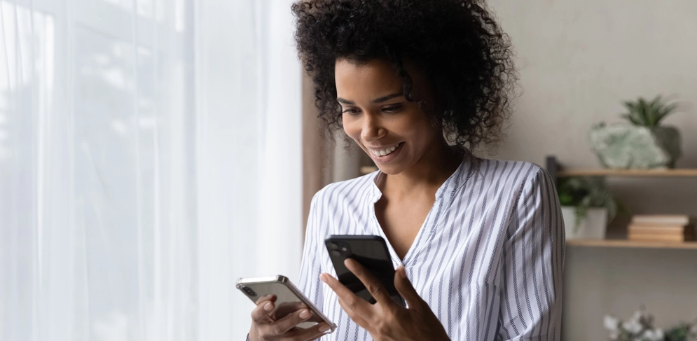 Ein Frau hält in der einen Hand ihr altes und in der anderen ihr neues günstiges Handy 