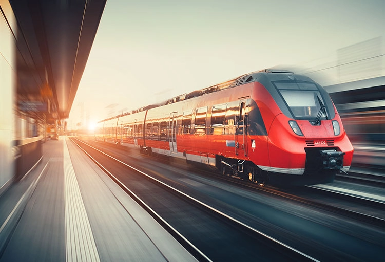 Roter Zug fährt durch einen Bahnhof